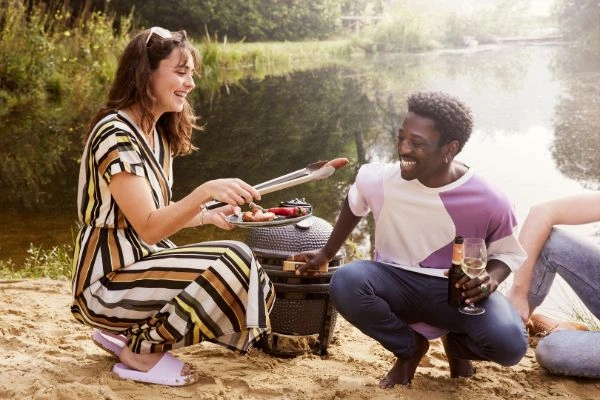 Doua persoane cu gratar Original Compact Grill Guru in natura,langa apa.